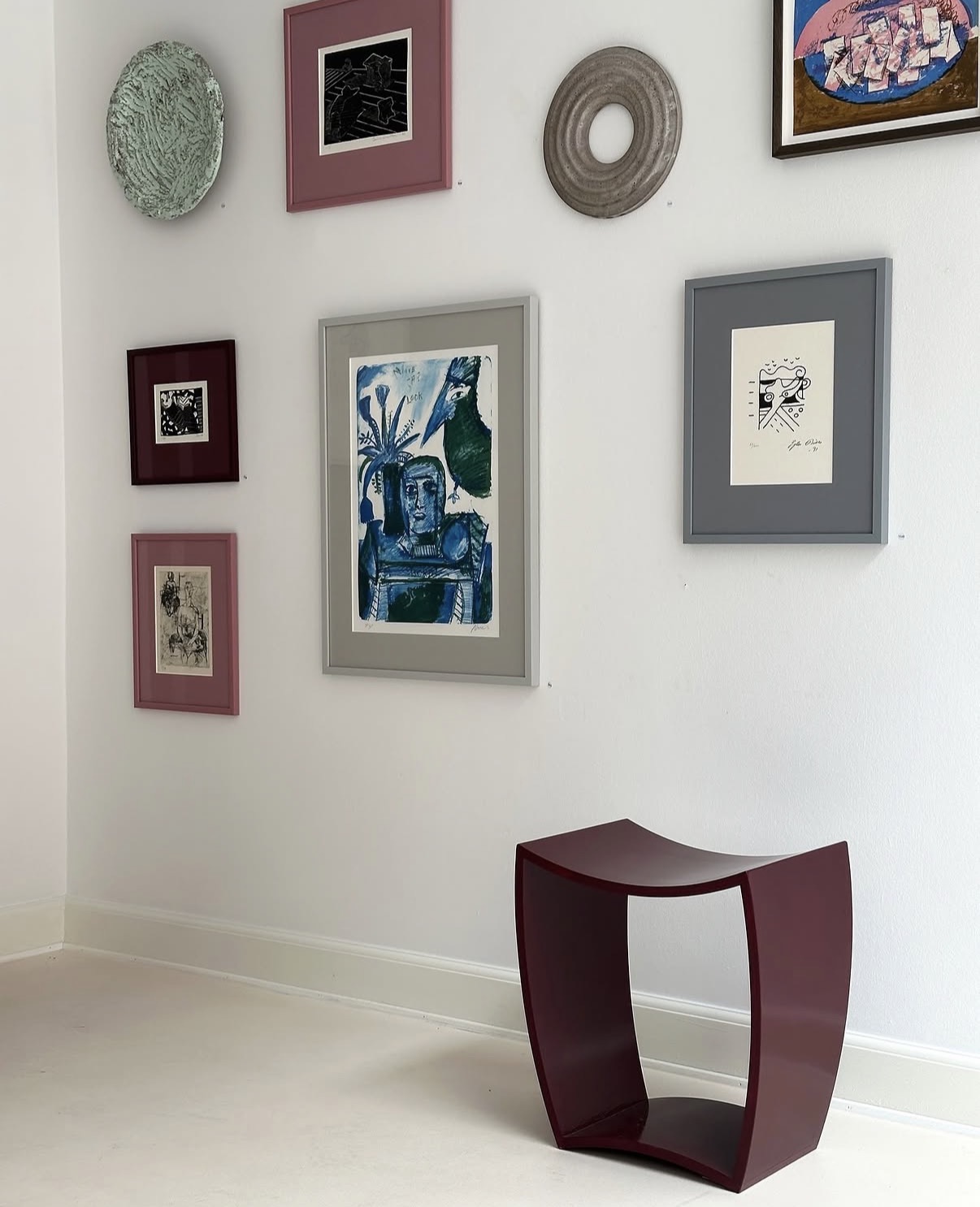 Curated gallery wall arrangement with mixed framed prints and ceramic pieces