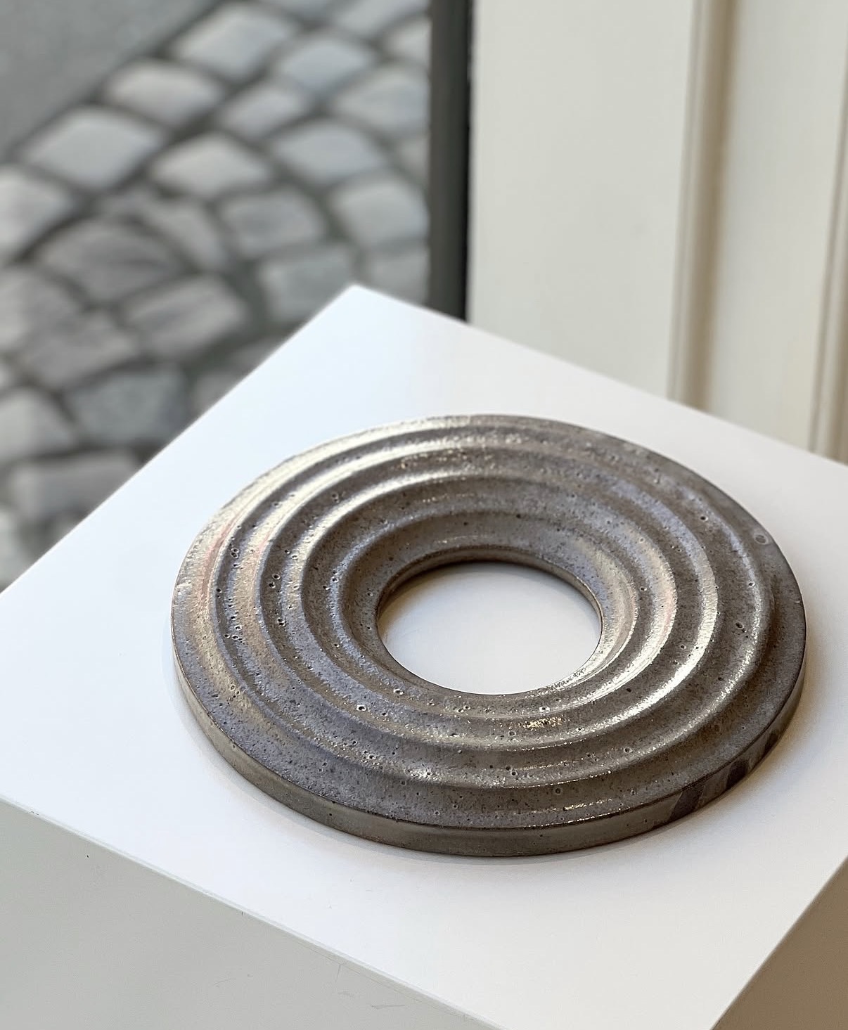 Ceramic sculptural object displayed on a plinth in the gallery window
